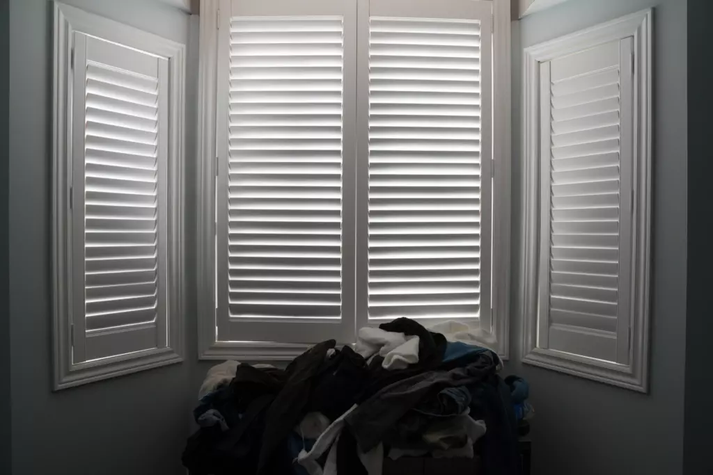 window with shutters in a bedroom from JP Blinds